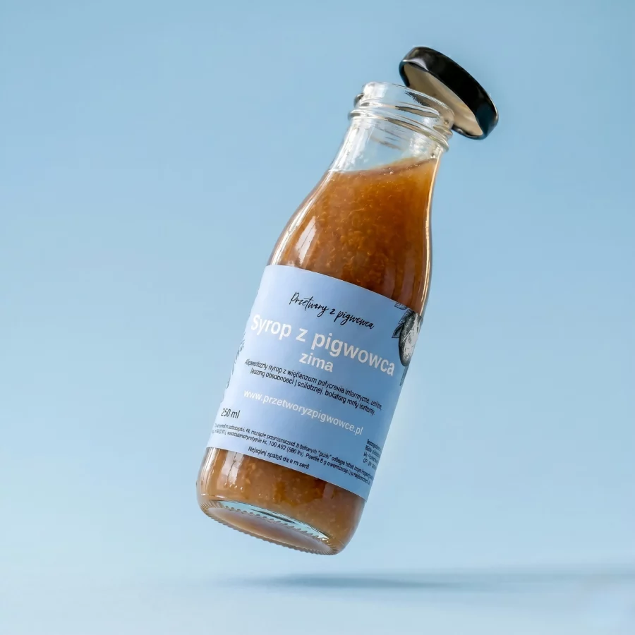 Butelka syropu z pigwowca zimowego na tle błękitnego nieba, 250 ml, etykieta informacyjna.