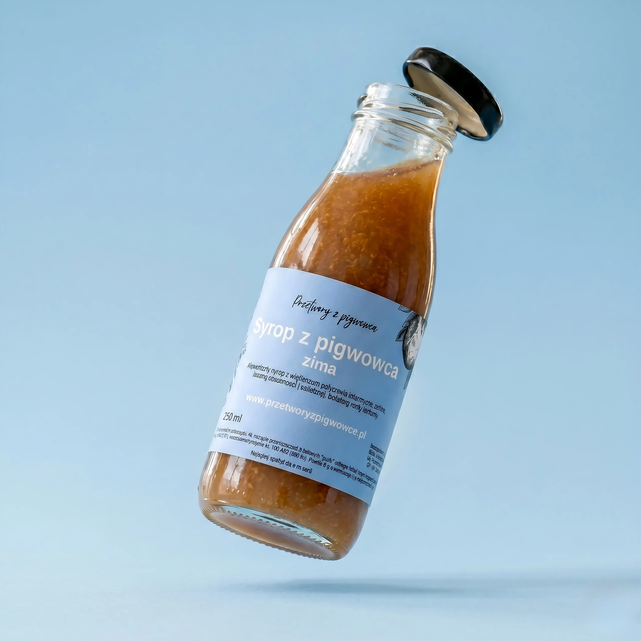 Butelka syropu z pigwowca zimowego na tle błękitnego nieba, 250 ml, etykieta informacyjna.
